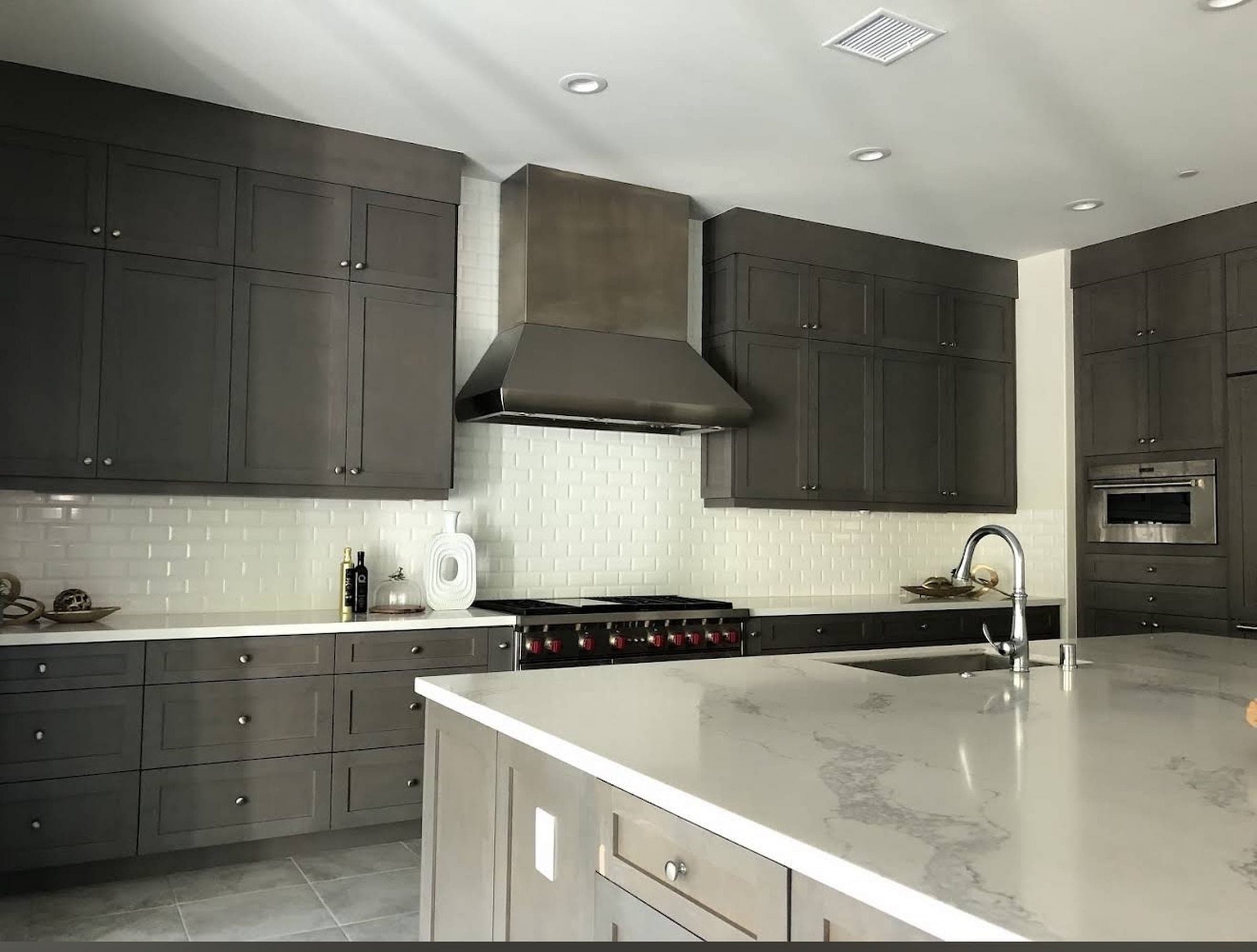 Cabinet style example — charcoal cabinetry with a white island and subway tile