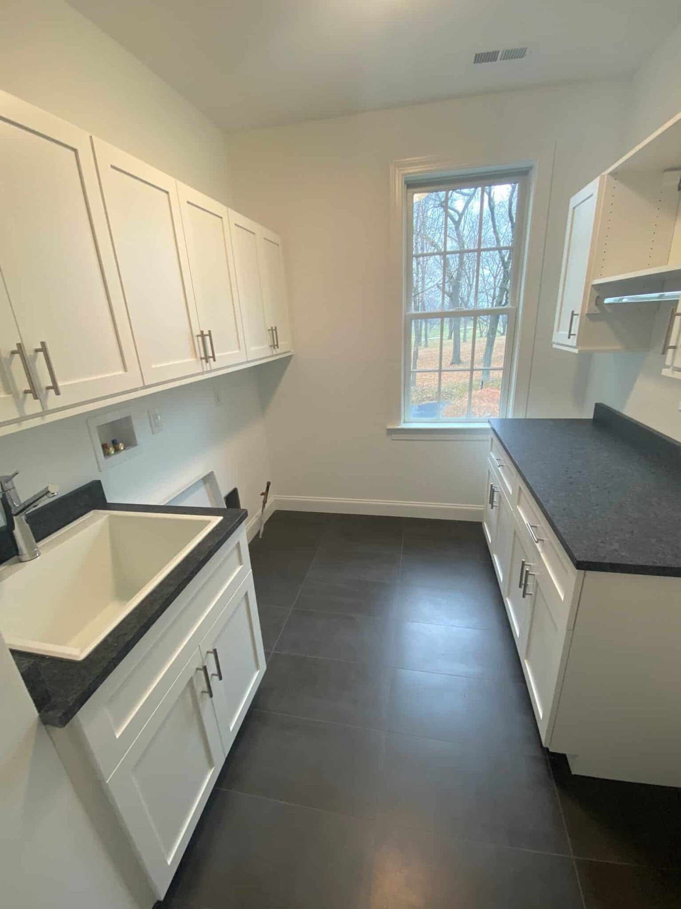 Organized-space inspiration: a laundry room with white cabinetry, a utility sink and a dark countertop