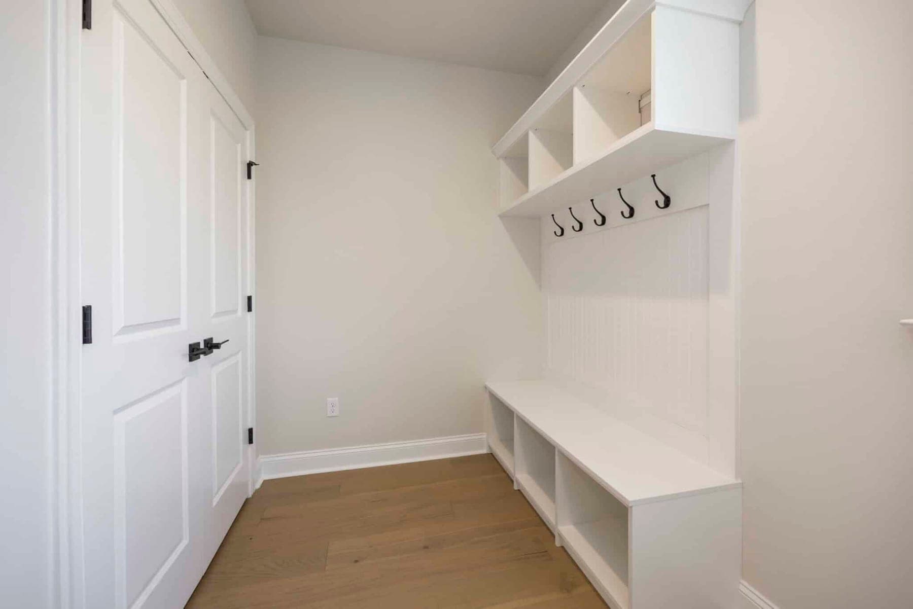Organized-space inspiration: a white mudroom bench with hooks, cubbies and shoe storage