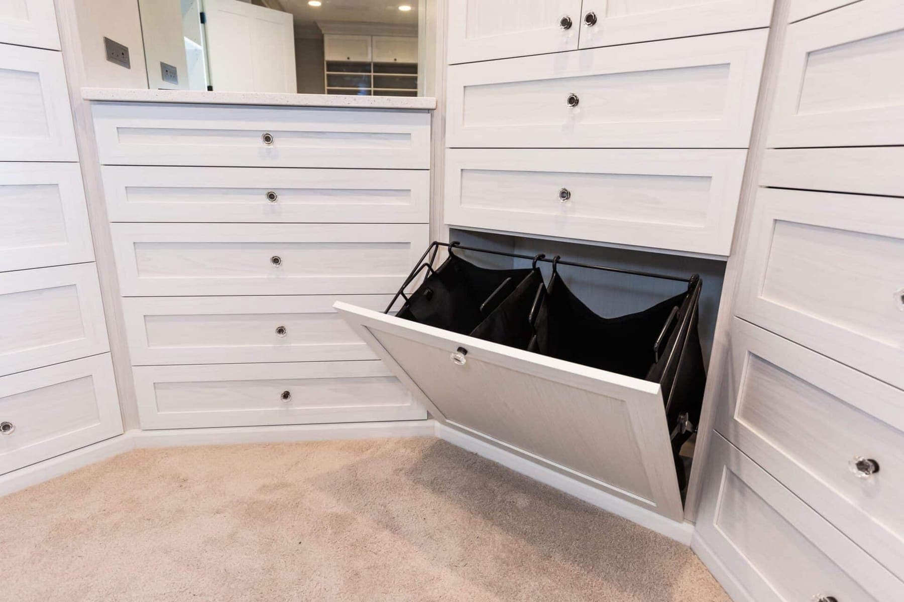 Organized-space inspiration: a white walk-in closet with full drawer banks and tilt-out hampers
