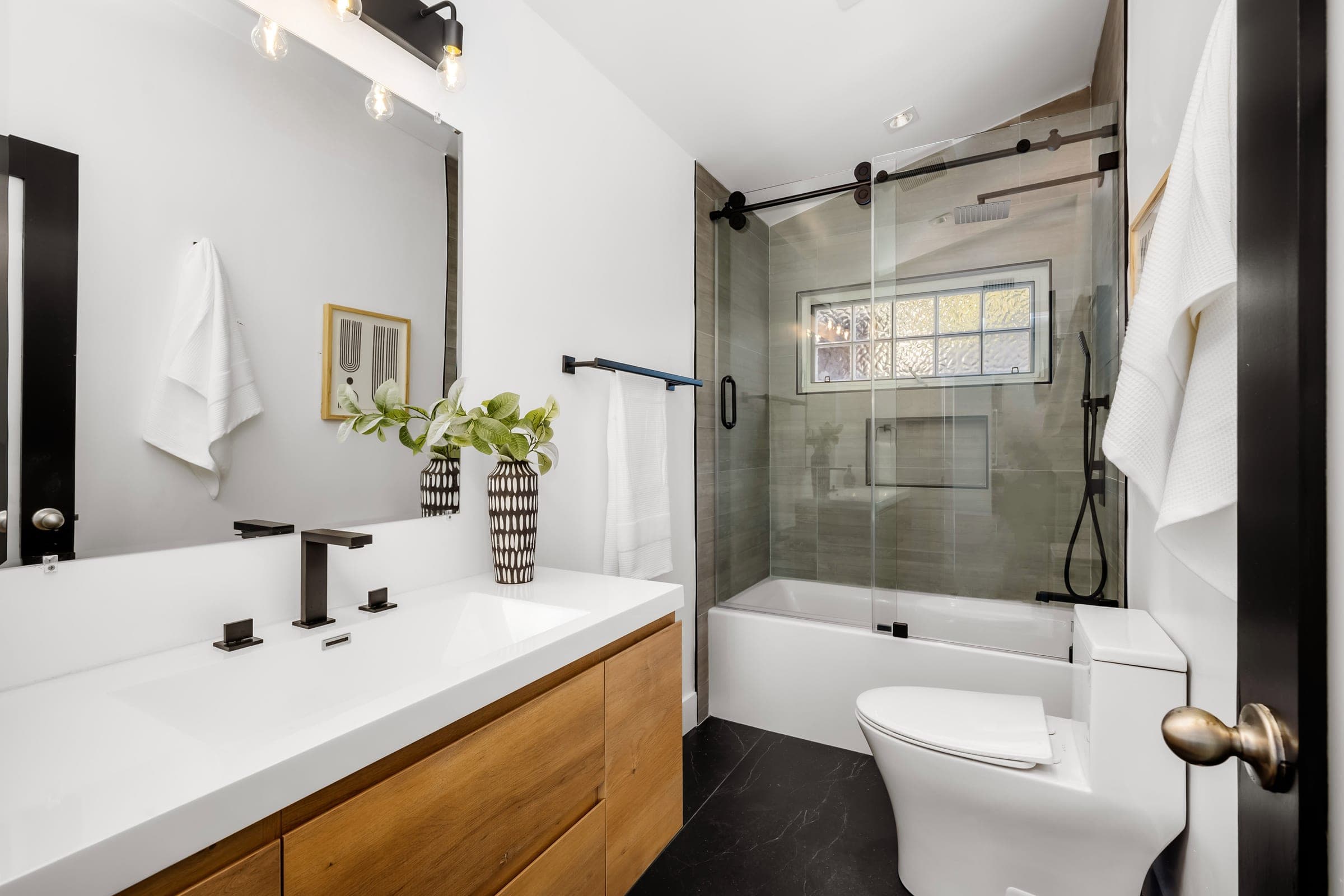 Cali Craft bathroom renovation with a floating timber vanity, a trough basin and a glass-framed tub surround