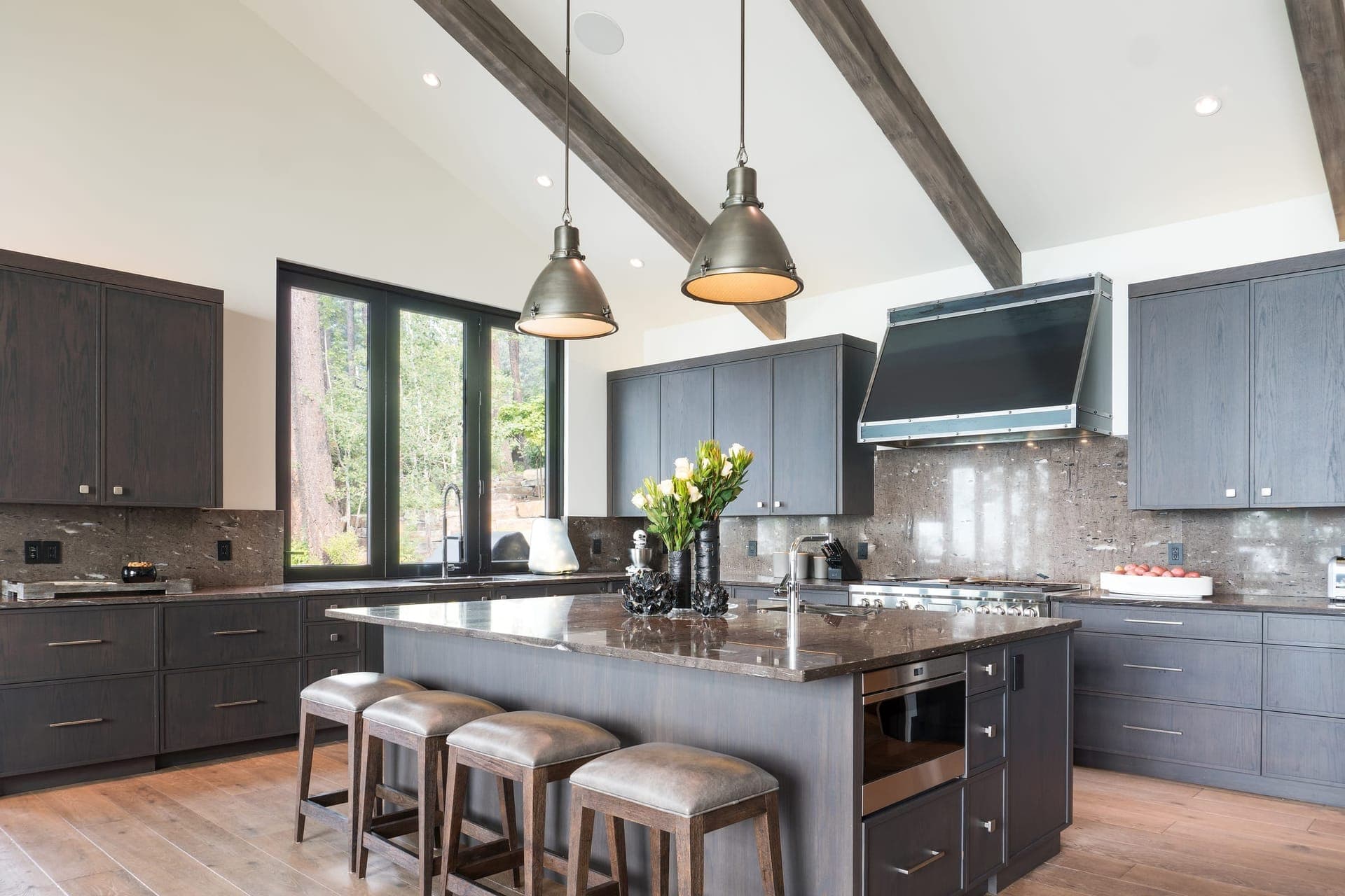 Cali Craft kitchen renovation with deep navy cabinetry, exposed timber ceiling beams, a granite island and bar seating