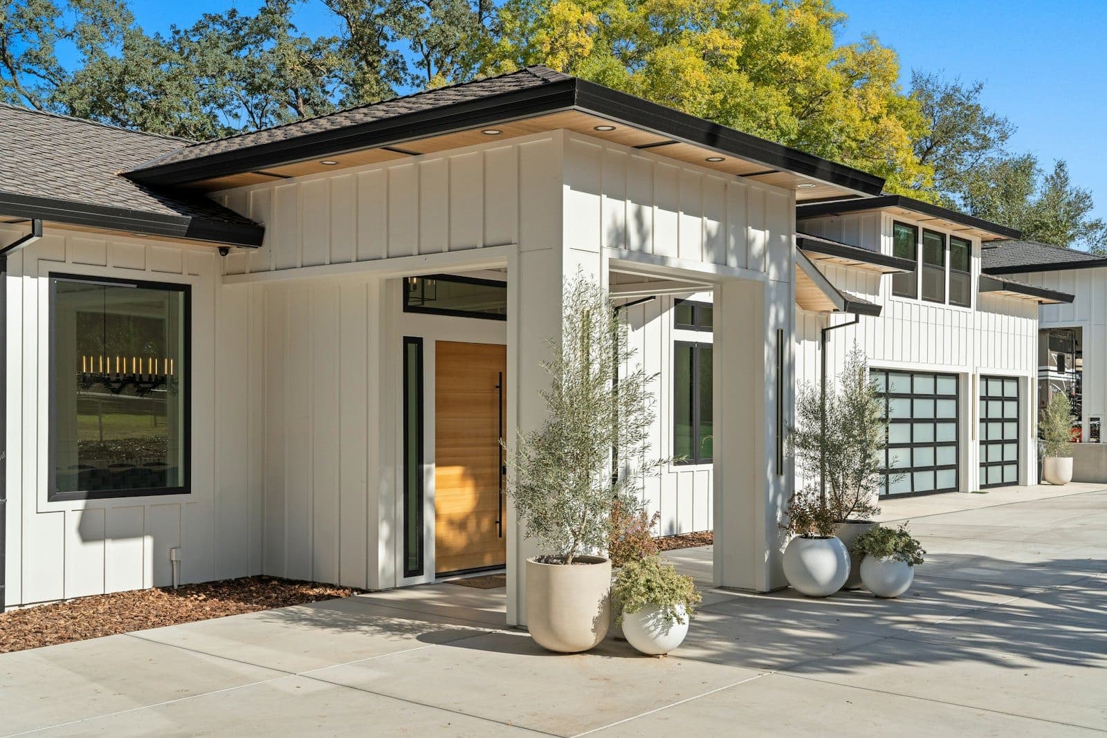 Stock concept image of a modern farmhouse entry with white board-and-batten siding and black trim — not an actual Cali Craft Renovations project