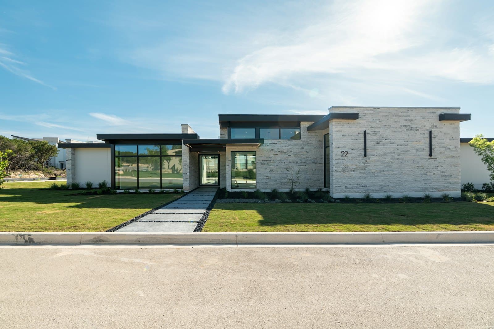 Stock concept image of a single-storey contemporary home in pale stone with full-height windows — not an actual Cali Craft Renovations project