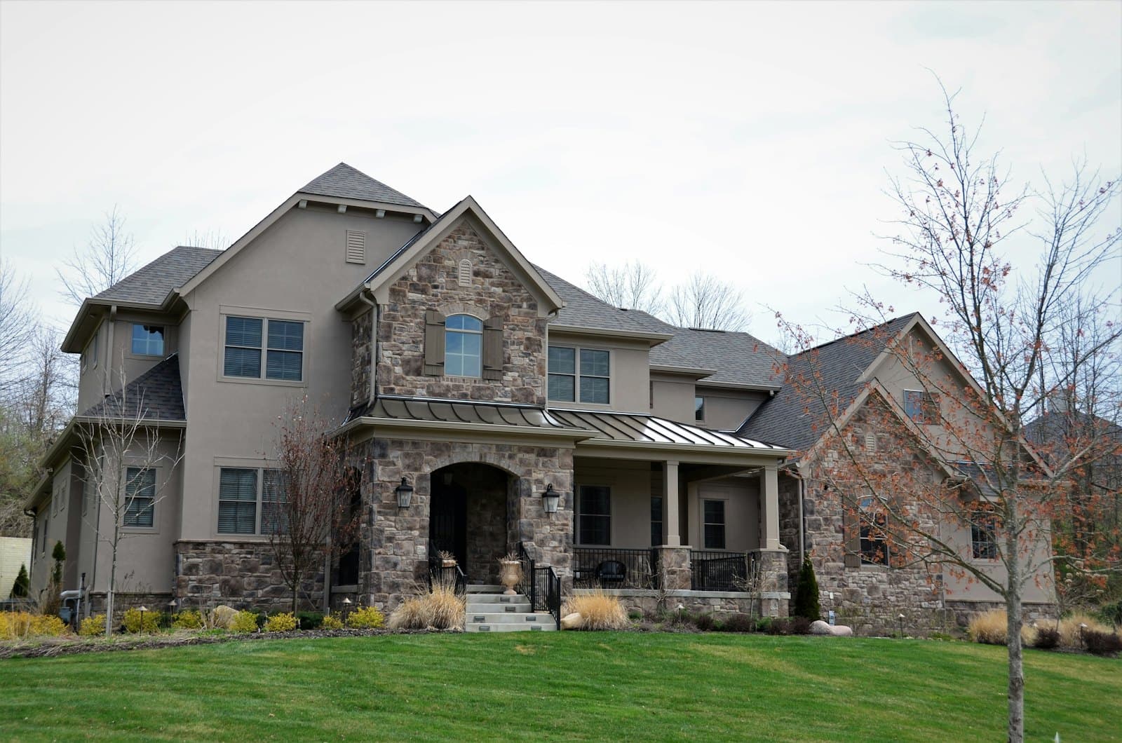 Stock concept image of a stucco-and-stone two-storey home with a gabled entry — not an actual Cali Craft Renovations project