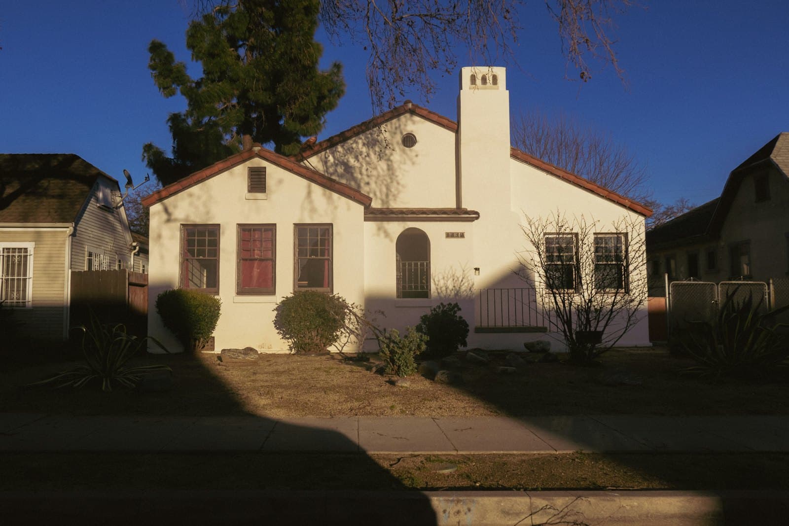 Stock concept image of a white stucco bungalow with a red door and red shutters — not an actual Cali Craft Renovations project